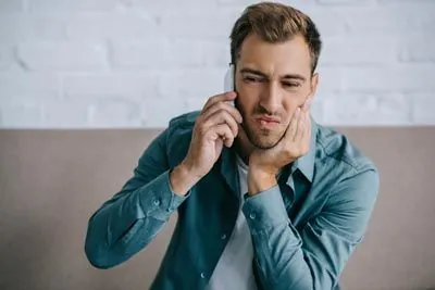 man holding his mouth due to tooth pain