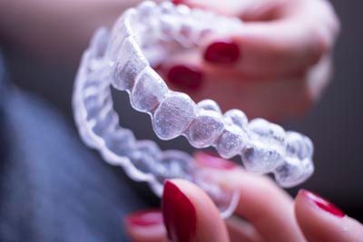 closeup of a woman holding her Reveal clear aligners