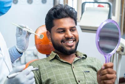 man looking in the mirror after getting his teeth cleaned at Ankeny Dental Professionals in Ankeny, IA